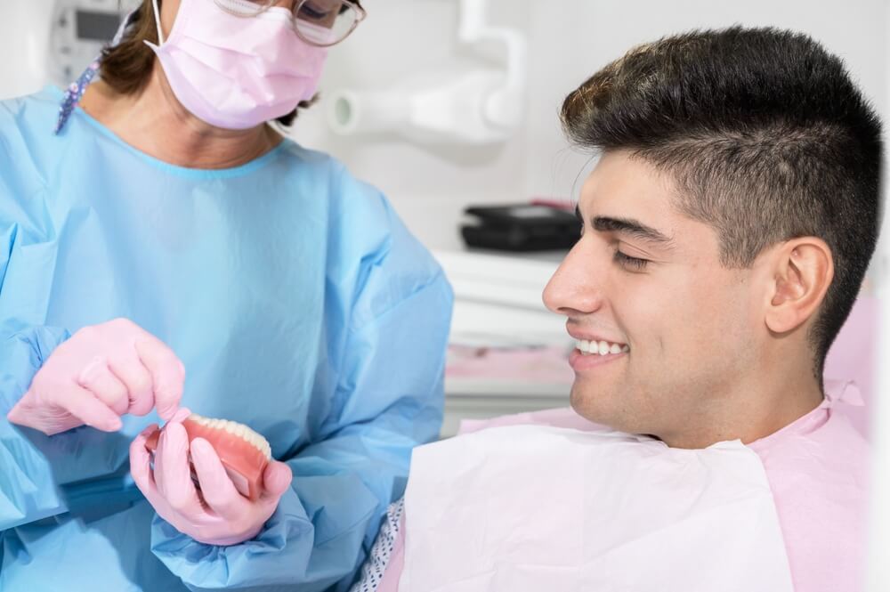 стоматолог рассказывает пациенту про лечение на элайнерах